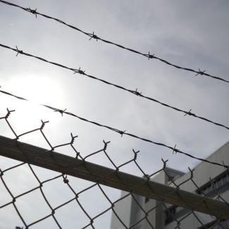 Grey sky seen through chain link fence and barbed wire